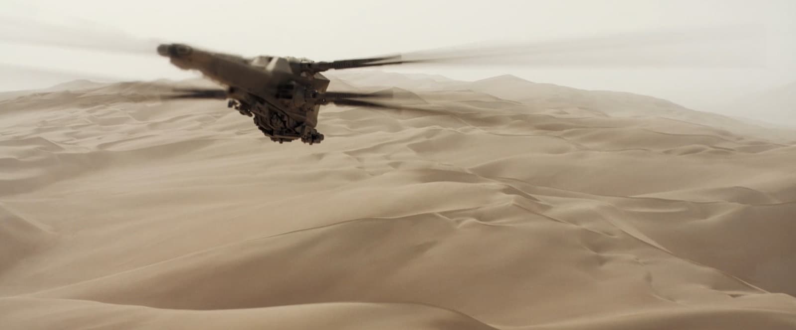 Летательный аппарат, напоминающий стрекозу летит над бескрайними просторами пустыни