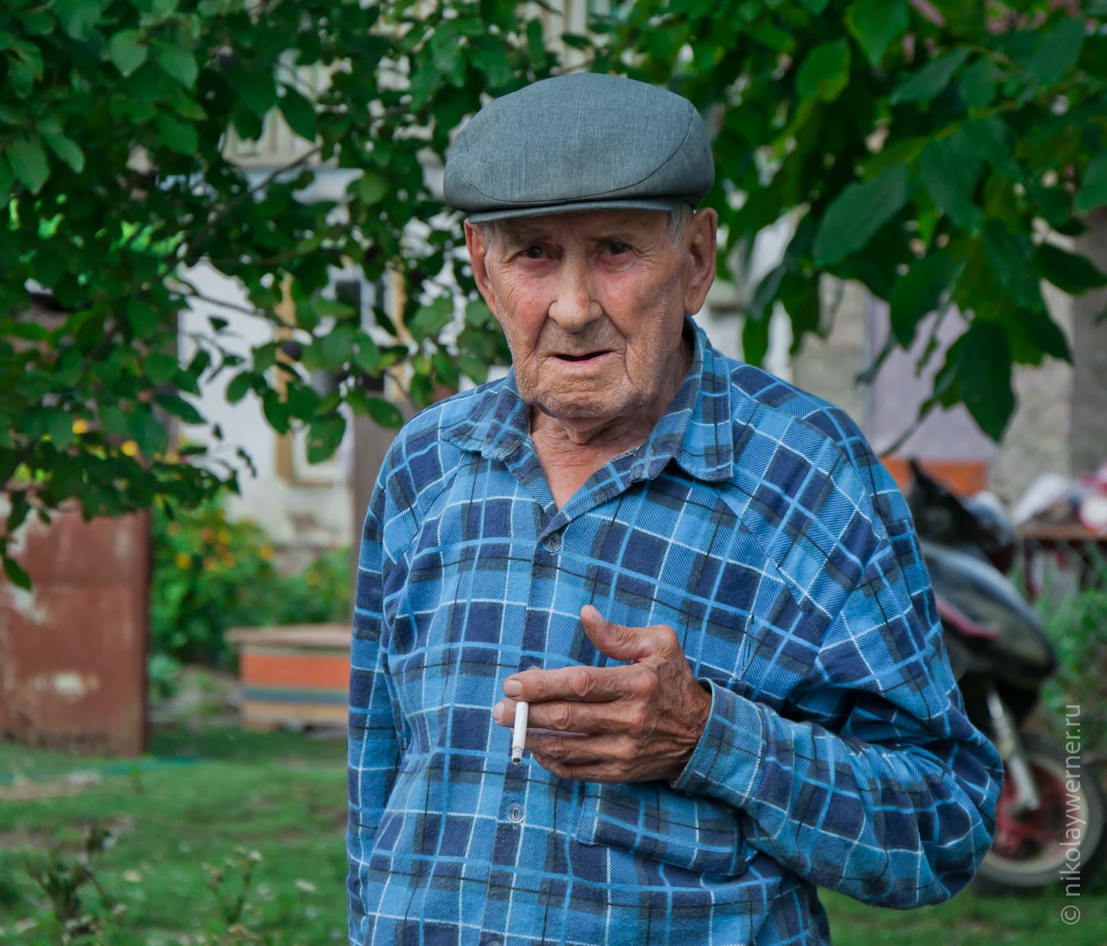 Дедушка из Верхнеадагума. В синей клетчатой рубашке, серой кепке и с сигаретой в руках