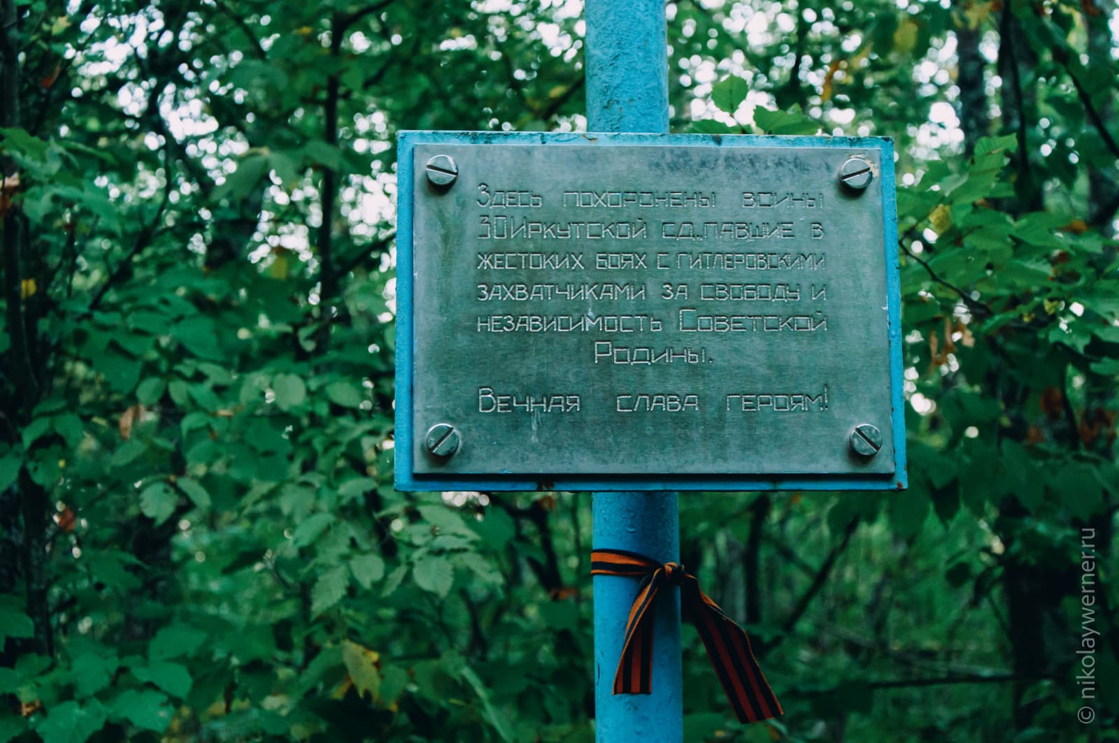 Синяя труба, на ней металлическая табличка с надписью: "Здесь похоронены воины 30-й Иркутской сд павшие в жестоких боях с гитлеровскими захватчиками за свободу и независимость Советской Родины. Вечная слава героям.«
