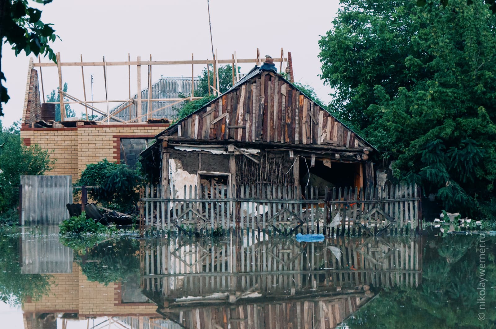 Наводнение в Крымске. Обширное поле воды на улице на фоне побитого стихией частного дома