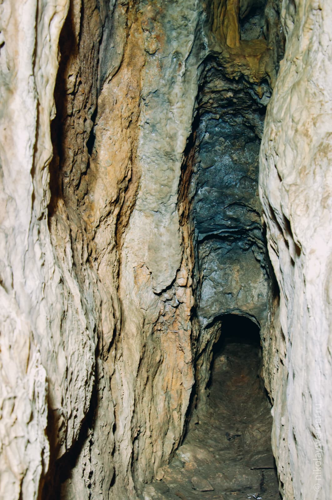 Внутри пещеры. Очень узкий, но высокий проход с вертикальными стенами. Впереди высота резко уменьшается и пещера превращается в узкую нору