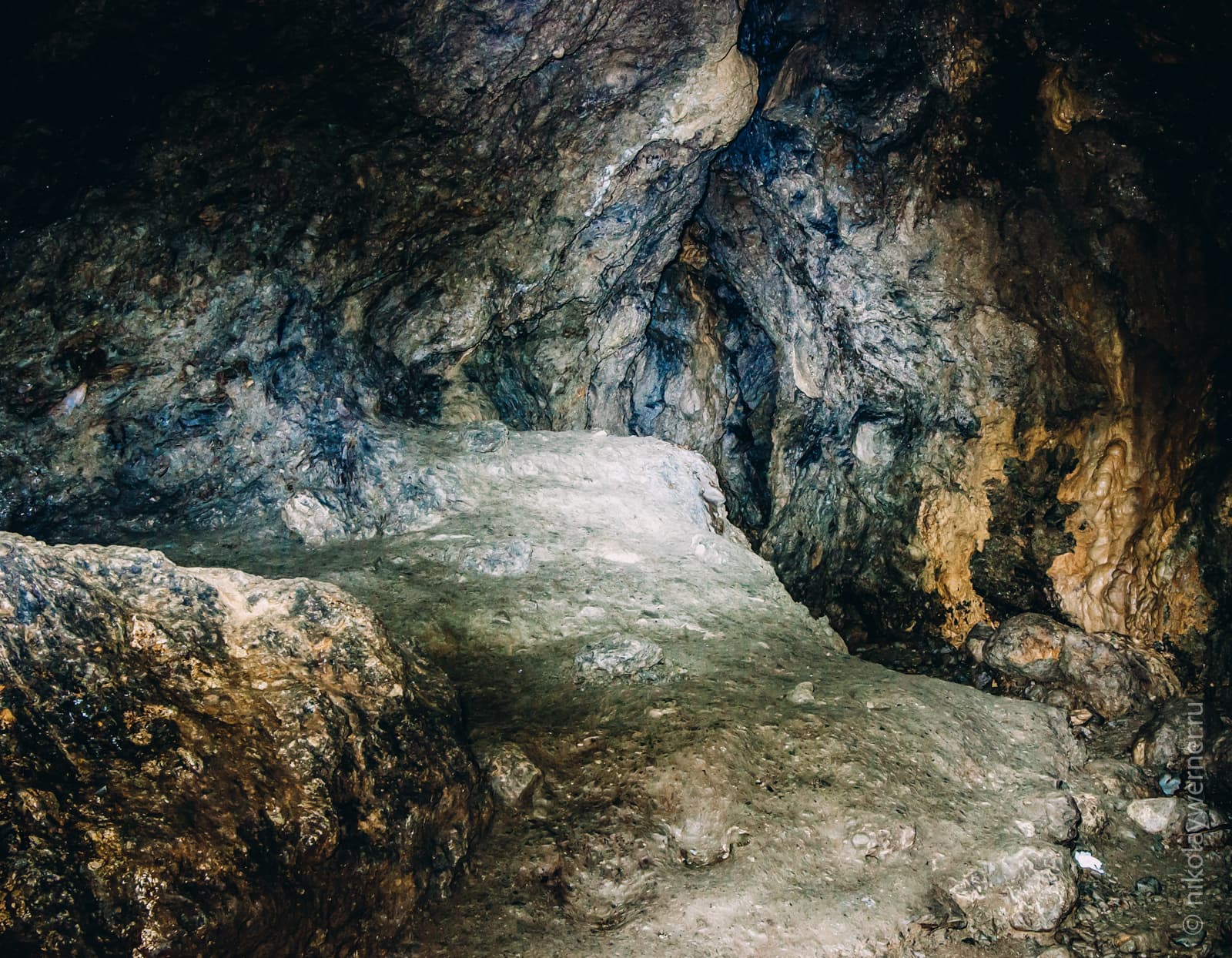 Широкий зал внутри пещеры с приподнятой площадкой слева. Камни, камни, камни